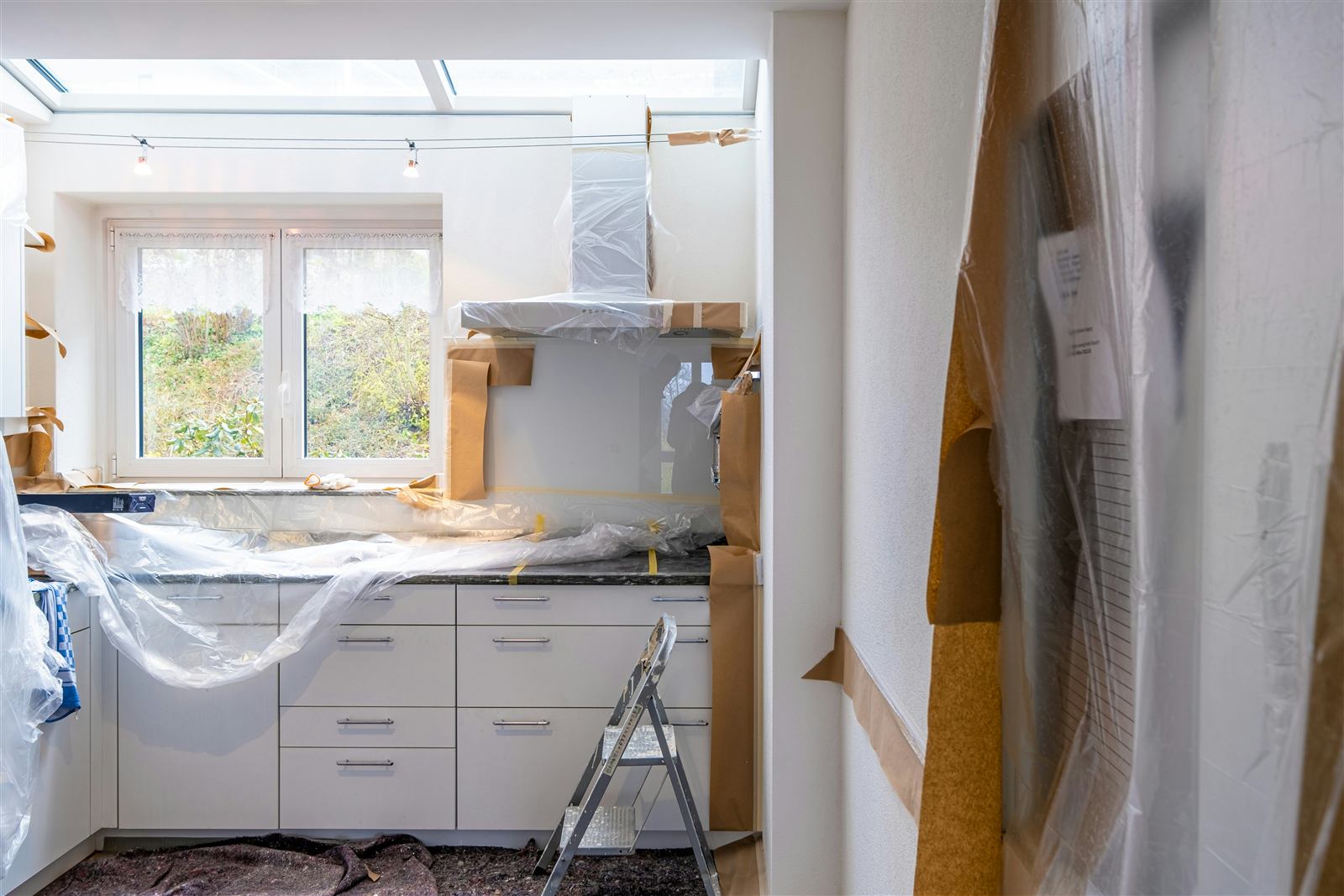 Kitchen mid-renovation during a Houston home addition project, with cabinets installed and surfaces protected in plastic sheeting (illustrative photo, not an actual job site)
