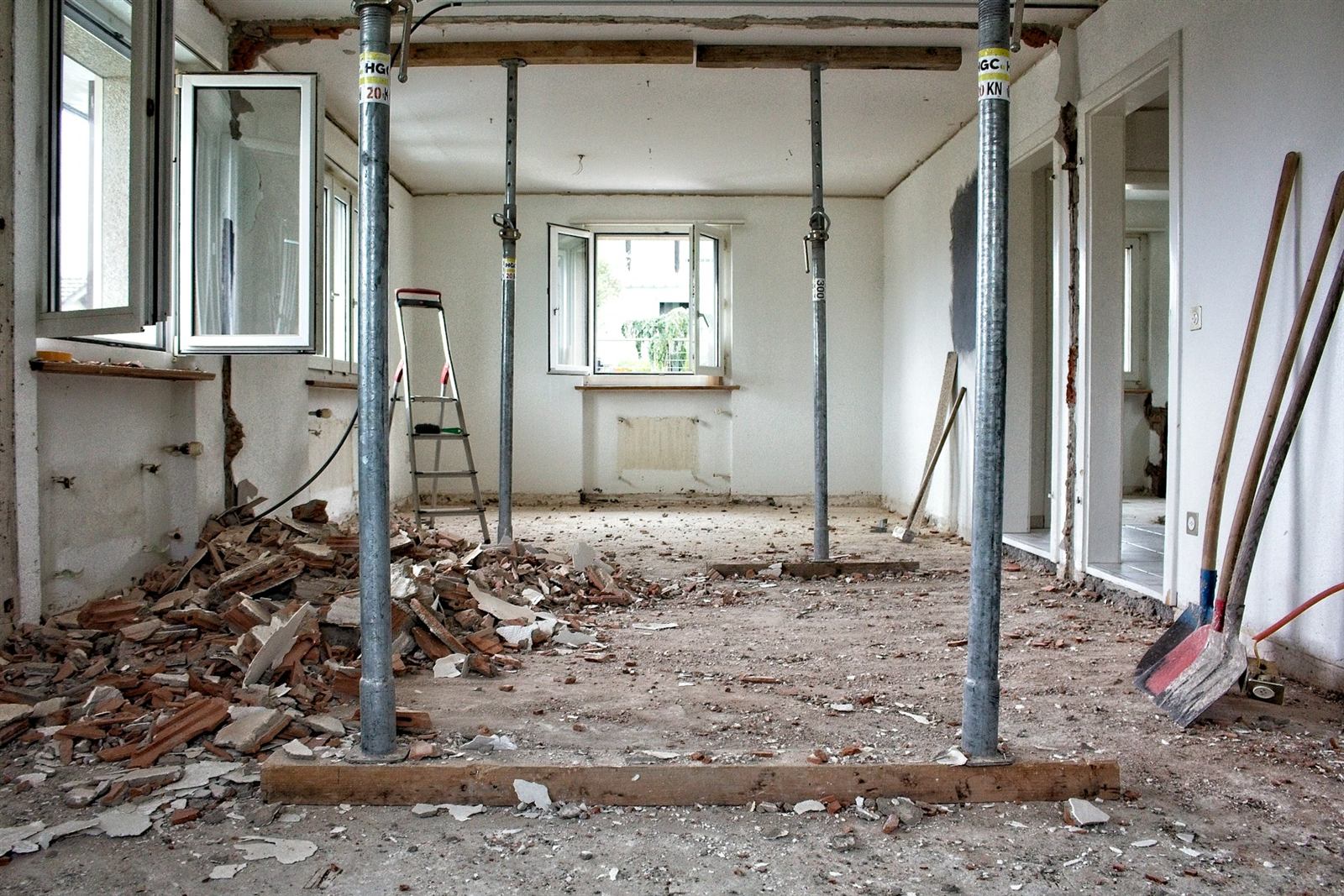 Interior room in a Houston home with adjustable steel shoring props supporting the ceiling during a load-bearing wall removal (illustrative photo, not an actual job site)